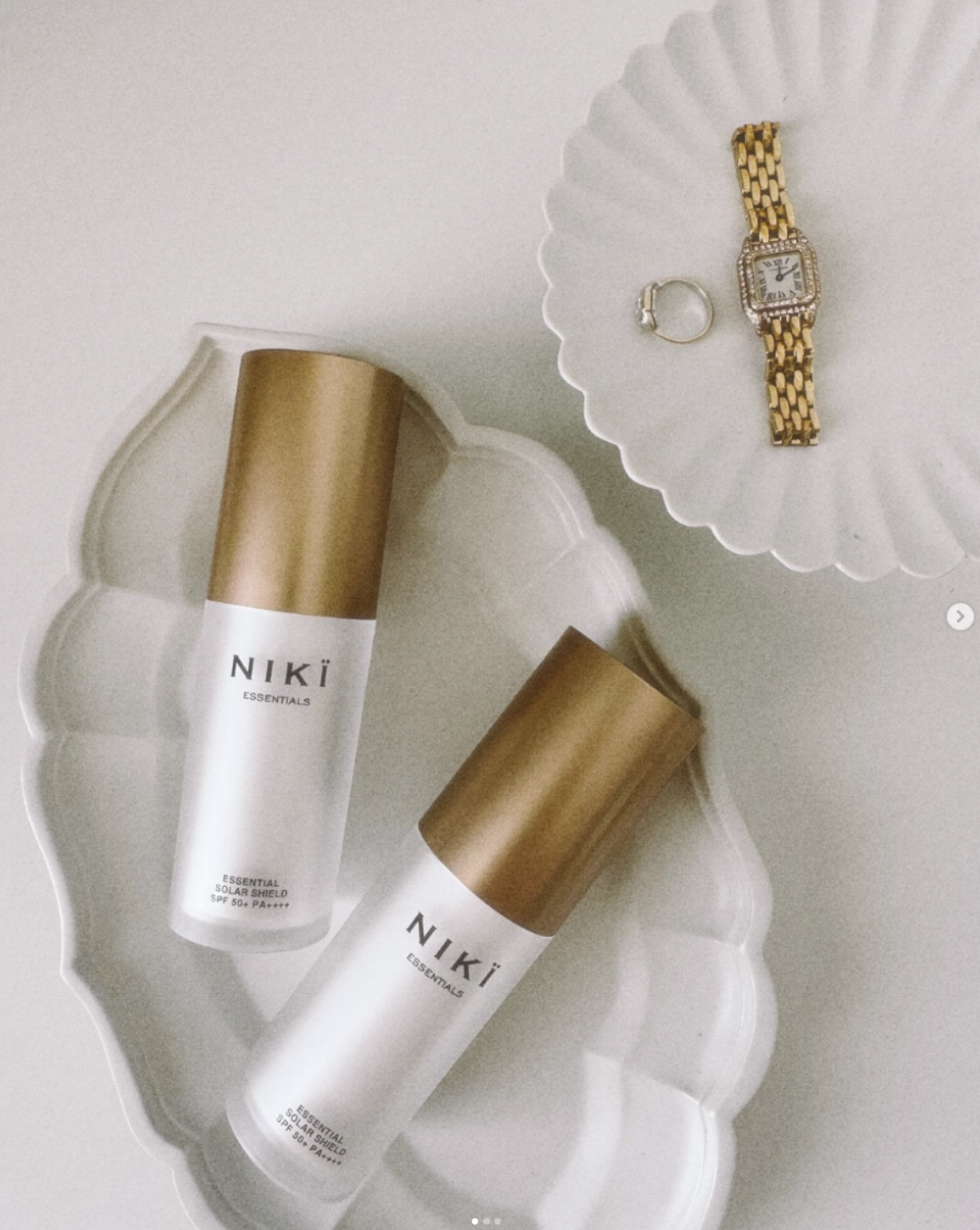 Two NIKI Essentials Solar Shield bottles on a ceramic tray